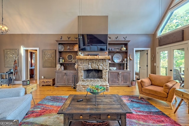 living room with french doors, a stone fireplace, hardwood / wood-style floors, and high vaulted ceiling