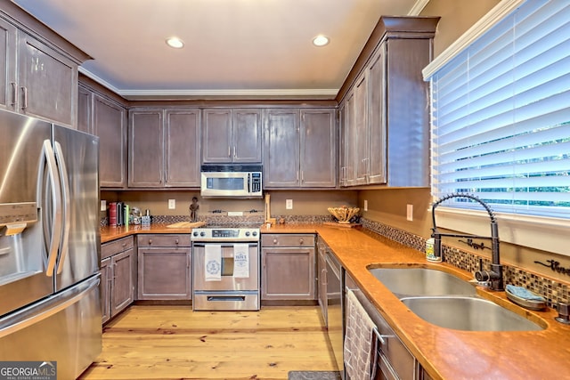 kitchen featuring appliances with stainless steel finishes, light wood-type flooring, sink, and wood counters