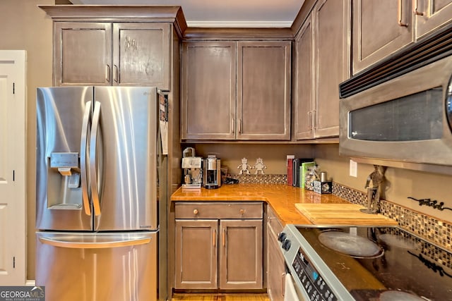 kitchen with stainless steel appliances, butcher block counters, and dark brown cabinetry