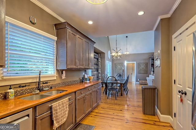 kitchen featuring crown molding, light hardwood / wood-style flooring, decorative light fixtures, sink, and a notable chandelier