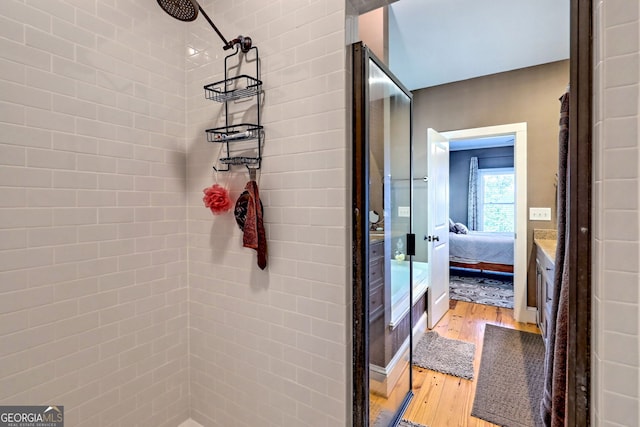 bathroom with a tile shower and hardwood / wood-style floors