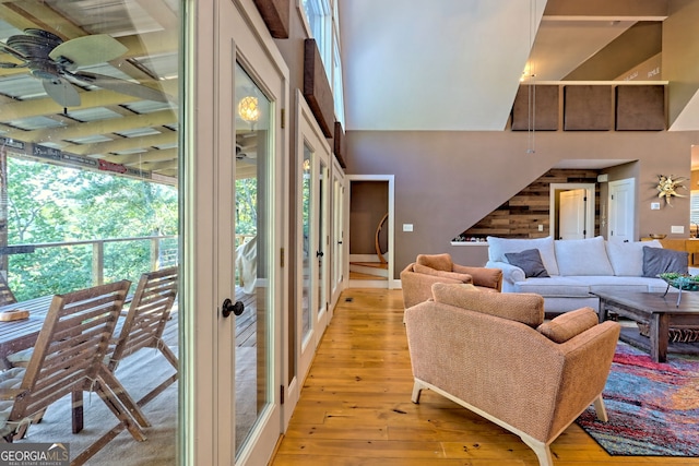 living room with a high ceiling, ceiling fan, light hardwood / wood-style flooring, and french doors