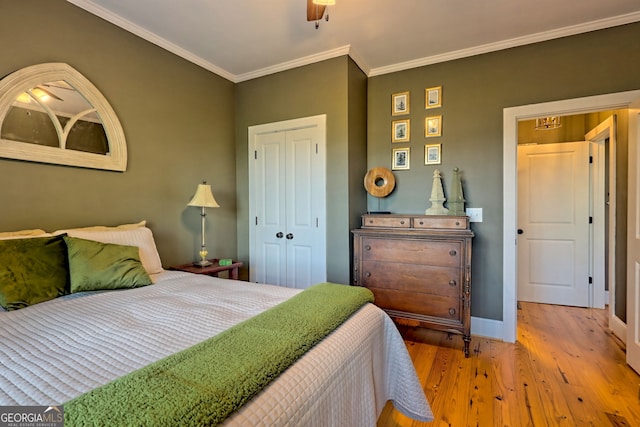 bedroom with light hardwood / wood-style floors, ornamental molding, ceiling fan, and a closet