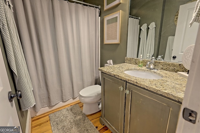 full bathroom with shower / bathtub combination with curtain, hardwood / wood-style floors, vanity, and toilet