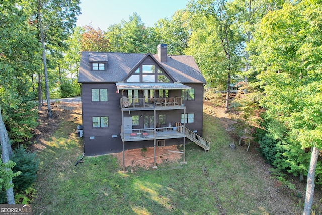 back of property featuring a balcony and a lawn