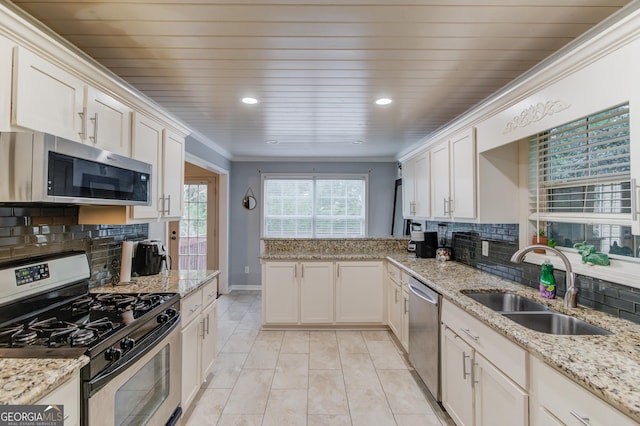 kitchen featuring sink, appliances with stainless steel finishes, tasteful backsplash, light stone counters, and white cabinetry