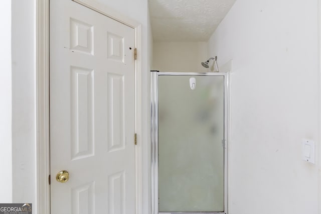 bathroom featuring a textured ceiling and walk in shower