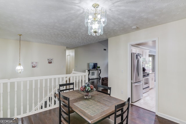 dining area featuring a textured ceiling, hardwood / wood-style flooring, and a notable chandelier