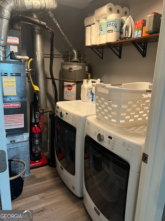 laundry room with washing machine and clothes dryer, wood-type flooring, and gas water heater