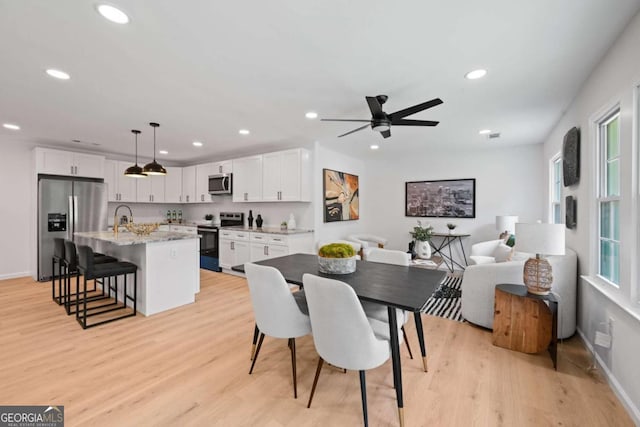 dining space featuring ceiling fan, light wood-type flooring, and sink