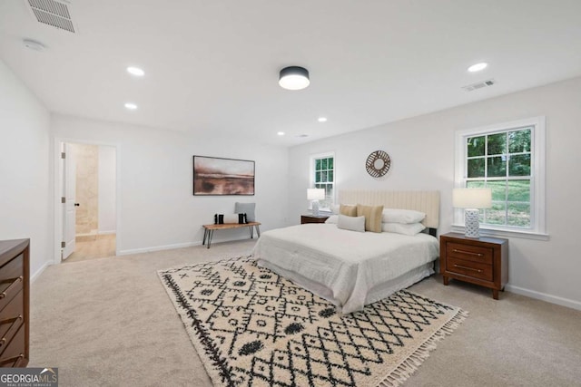 bedroom featuring ensuite bath and light colored carpet