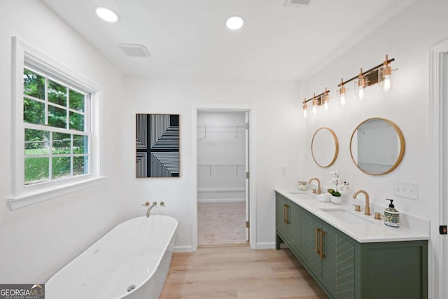 bathroom with a bathing tub, hardwood / wood-style floors, and vanity