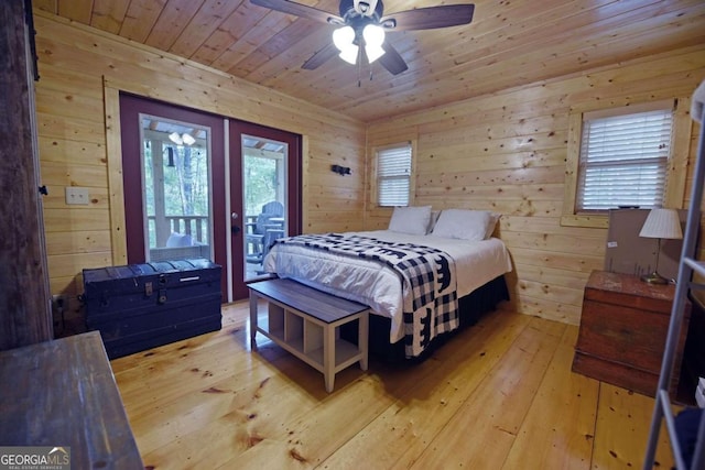 bedroom with light hardwood / wood-style flooring, wooden walls, ceiling fan, and access to exterior