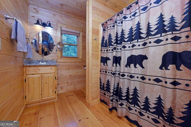 bathroom with wood-type flooring, vanity, and wooden walls