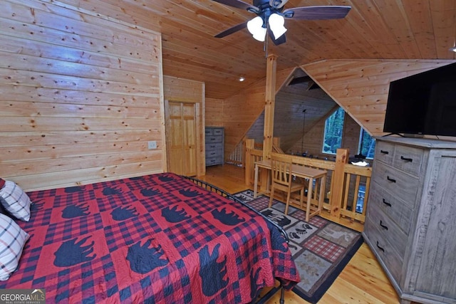 bedroom featuring ceiling fan, wooden walls, light hardwood / wood-style flooring, wooden ceiling, and vaulted ceiling