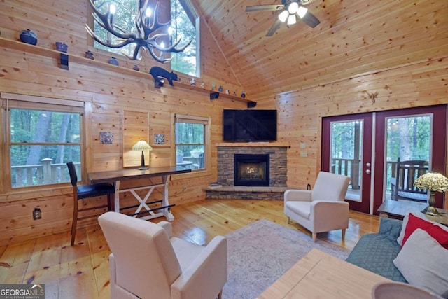 living room with high vaulted ceiling, wooden walls, light wood-type flooring, and french doors