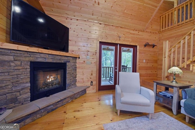 living area with wood ceiling, wood-type flooring, wood walls, a fireplace, and french doors