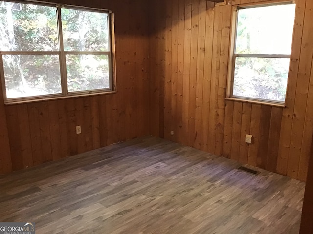 unfurnished room featuring dark wood-type flooring and wooden walls