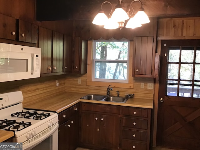 kitchen featuring plenty of natural light, an inviting chandelier, white appliances, and sink