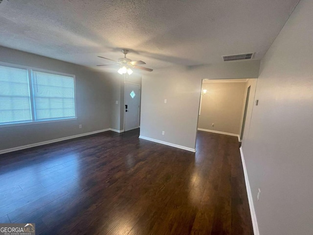 empty room with ceiling fan, dark wood-type flooring, and a textured ceiling