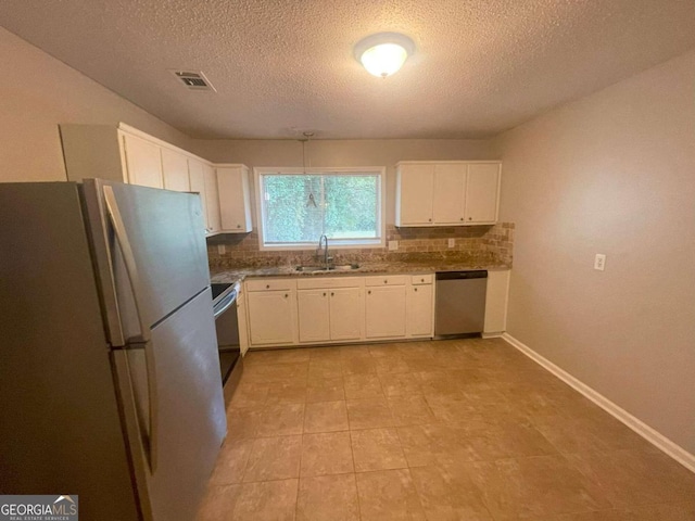 kitchen with a textured ceiling, tasteful backsplash, sink, white cabinetry, and stainless steel appliances