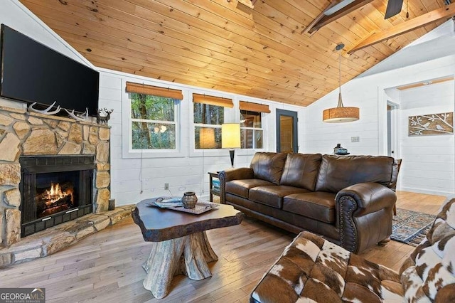 living room featuring lofted ceiling with beams, a stone fireplace, wooden ceiling, light wood-type flooring, and wooden walls