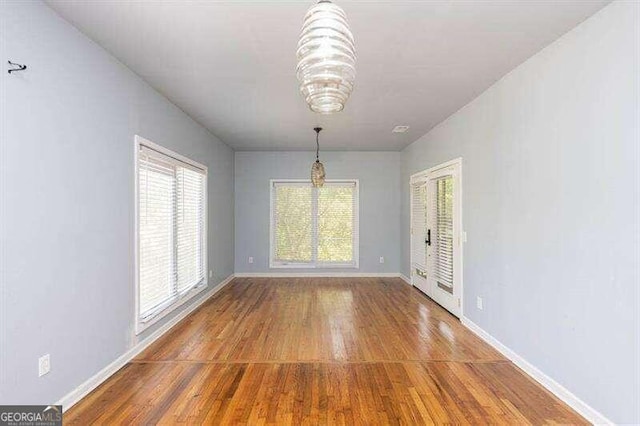 unfurnished dining area with an inviting chandelier and hardwood / wood-style flooring