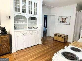 bar featuring white cabinets, light hardwood / wood-style floors, and white range oven