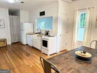 kitchen featuring hardwood / wood-style floors, white appliances, white cabinetry, and sink