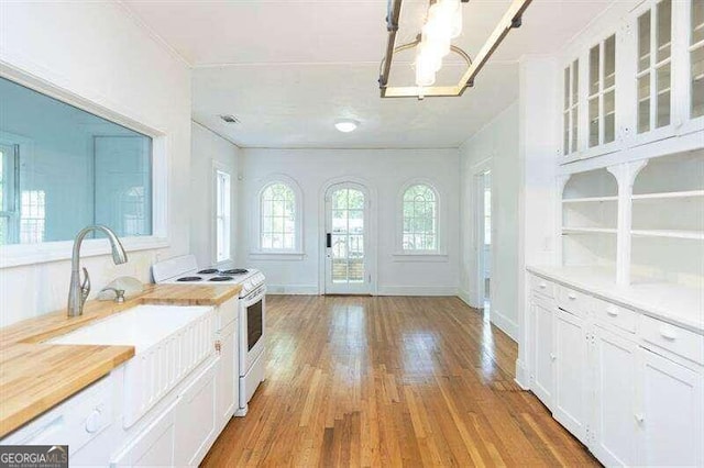 kitchen with white cabinetry, electric range, hanging light fixtures, and hardwood / wood-style flooring