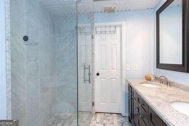 bathroom with a tile shower and vanity