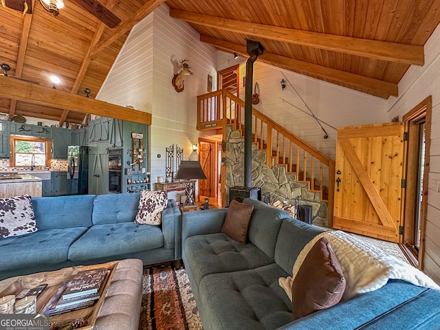 living room featuring wood ceiling, wooden walls, high vaulted ceiling, a wood stove, and beam ceiling