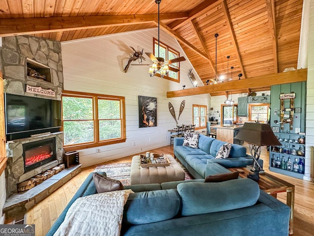 living room featuring wood walls, high vaulted ceiling, beam ceiling, ceiling fan, and wood-type flooring