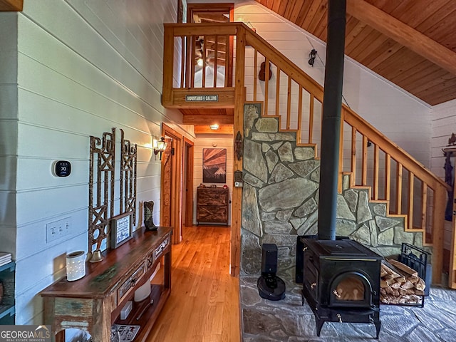 stairs with wood ceiling, wood walls, wood-type flooring, vaulted ceiling with beams, and a wood stove