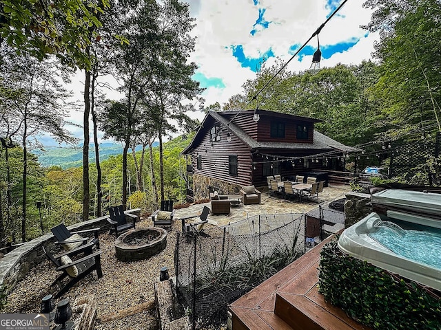 rear view of property featuring a deck and an outdoor living space with a fire pit