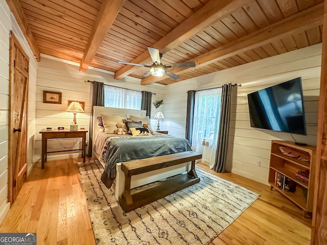 bedroom with wooden walls, light hardwood / wood-style floors, and beamed ceiling