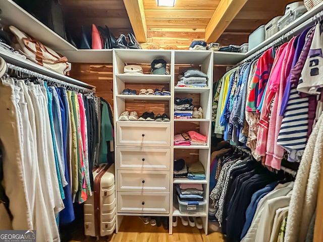 walk in closet featuring light wood-type flooring and beamed ceiling