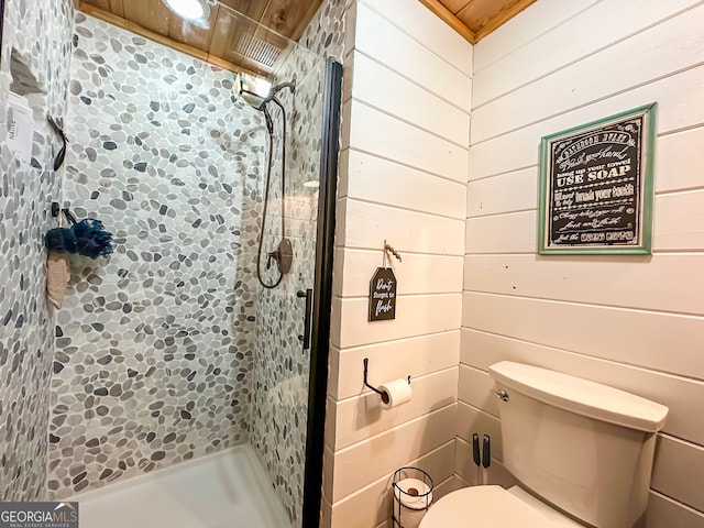 bathroom featuring toilet, wood walls, tiled shower, and wood ceiling