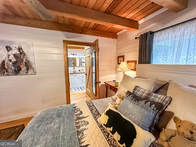 bedroom with hardwood / wood-style floors, wood walls, ensuite bath, wood ceiling, and beam ceiling