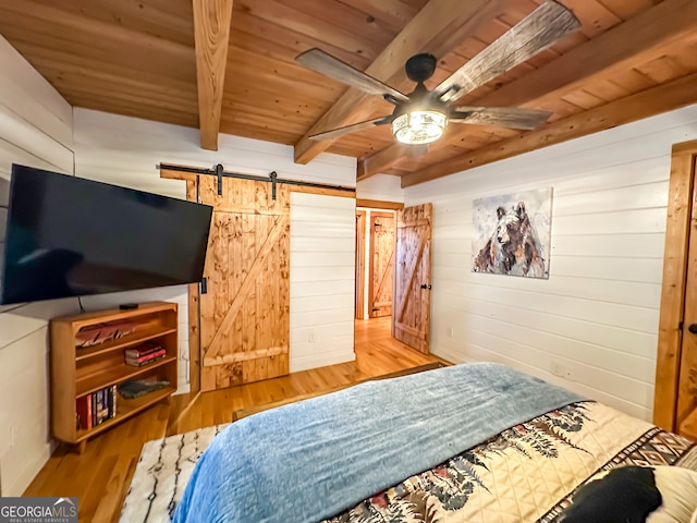 bedroom featuring wooden walls, hardwood / wood-style floors, a barn door, wooden ceiling, and beamed ceiling