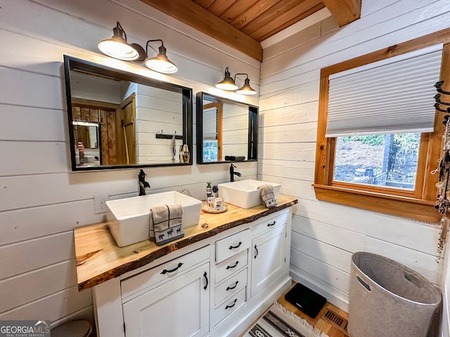 bathroom featuring wood ceiling, wood walls, and vanity