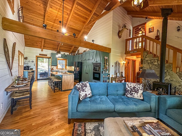 living room featuring wooden ceiling, a wood stove, light wood-type flooring, high vaulted ceiling, and beam ceiling