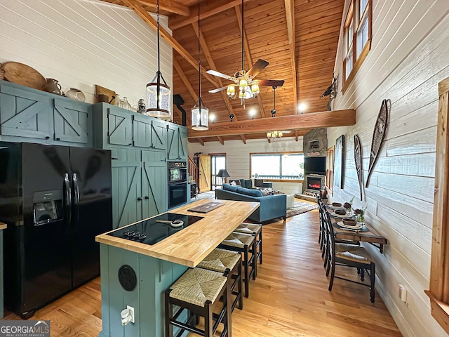 kitchen featuring black appliances, wooden walls, and beam ceiling