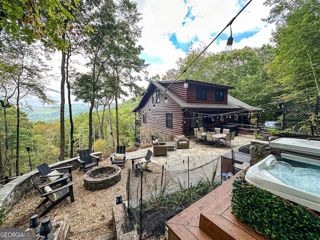 rear view of house with an outdoor living space with a fire pit