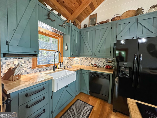 kitchen with sink, wooden ceiling, vaulted ceiling with beams, butcher block countertops, and black appliances