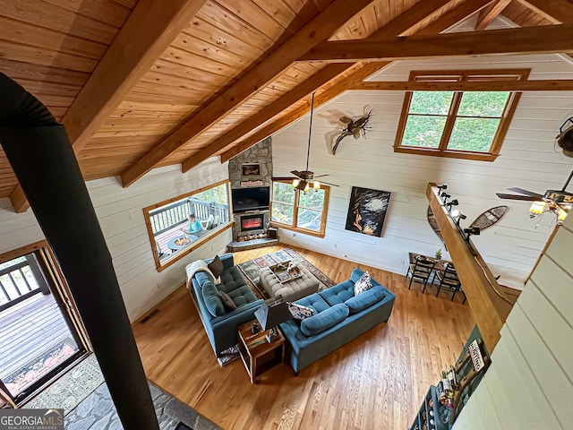 living room featuring wooden walls, vaulted ceiling with beams, ceiling fan, wood-type flooring, and wood ceiling