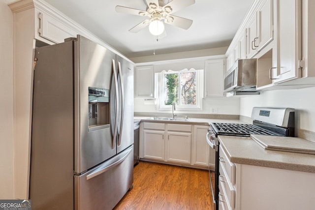 kitchen featuring sink, light hardwood / wood-style flooring, ceiling fan, appliances with stainless steel finishes, and white cabinetry