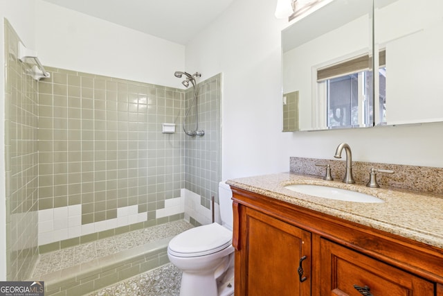 bathroom featuring vanity, toilet, and tiled shower