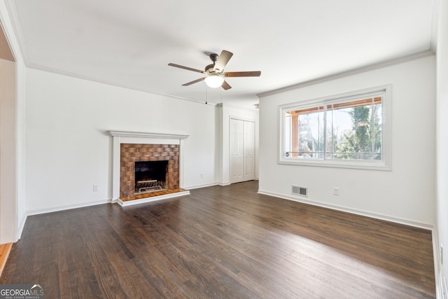 unfurnished living room featuring ceiling fan, dark hardwood / wood-style flooring, crown molding, and a brick fireplace