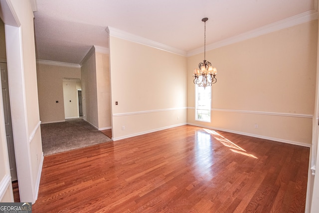 spare room with a notable chandelier, ornamental molding, and hardwood / wood-style flooring